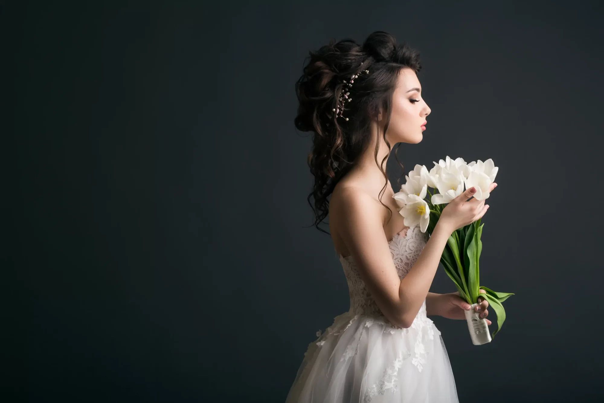 Een bruid met opgestoken haar en een boeket witte tulpen